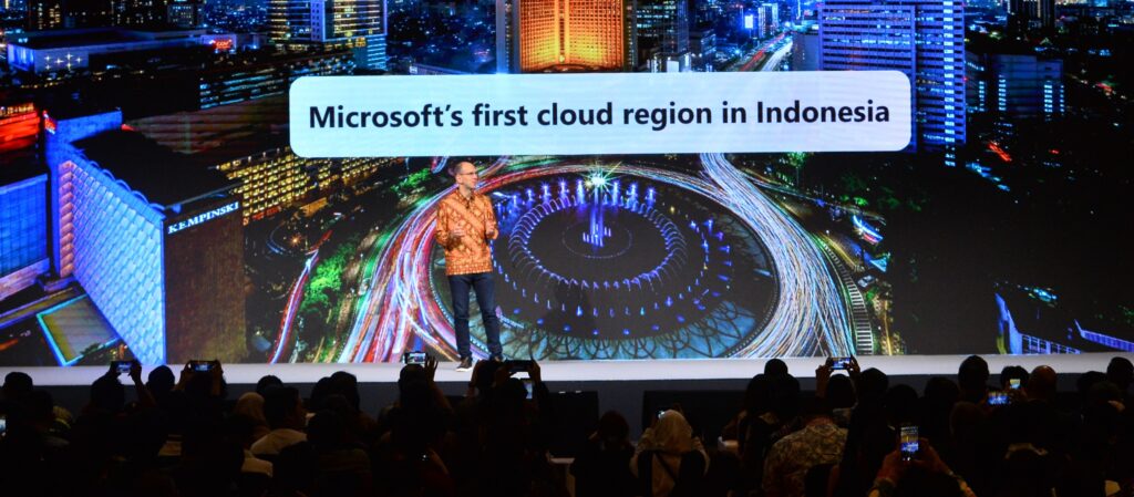 A man on stage, in front of the text "Microsoft's first cloud region in Indonesia"