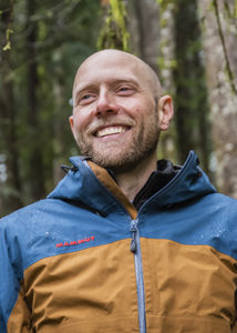 Lucas Joppa stands smiling with trees in the background